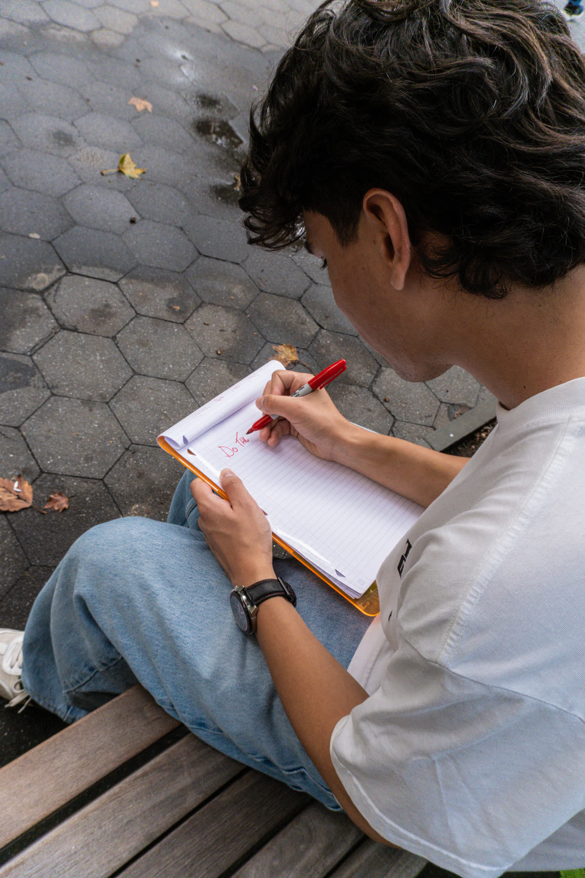 Second participant writing the next instruction while seated on a park bench